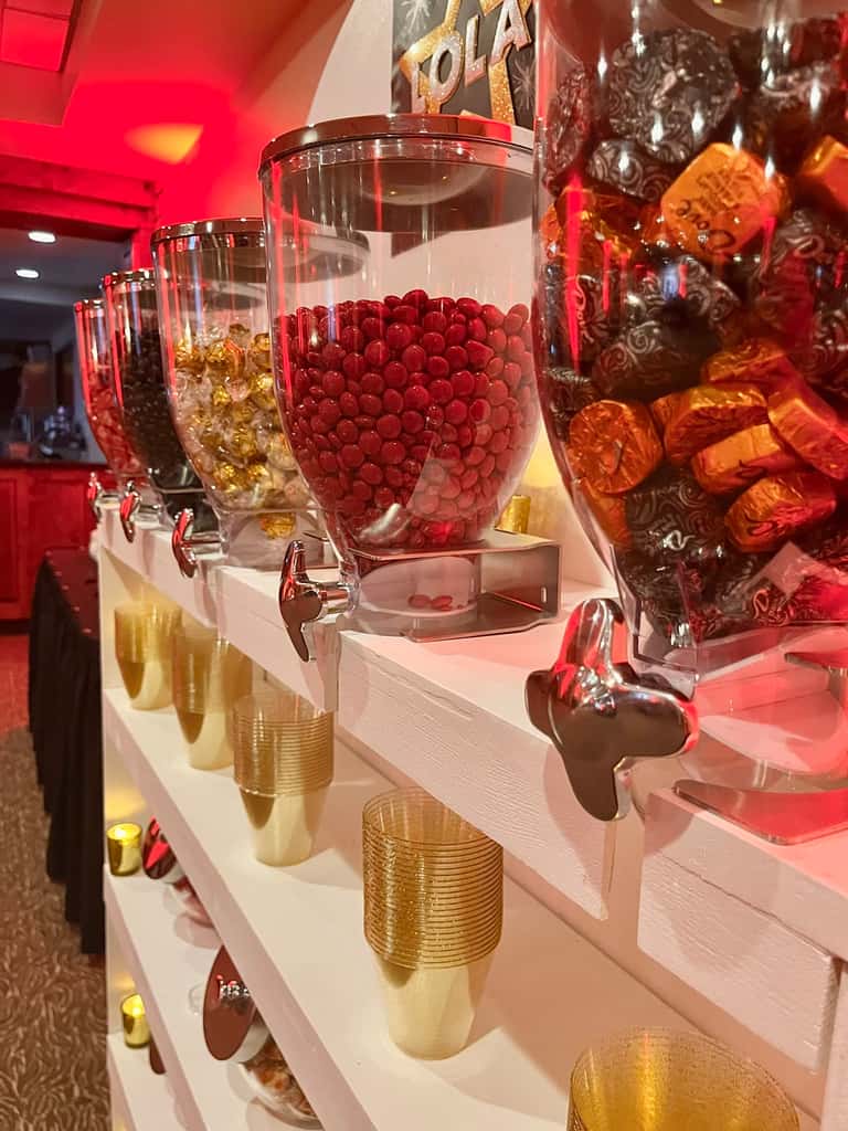 A candy wall of dispensers filled with colorful sweets and serving cups