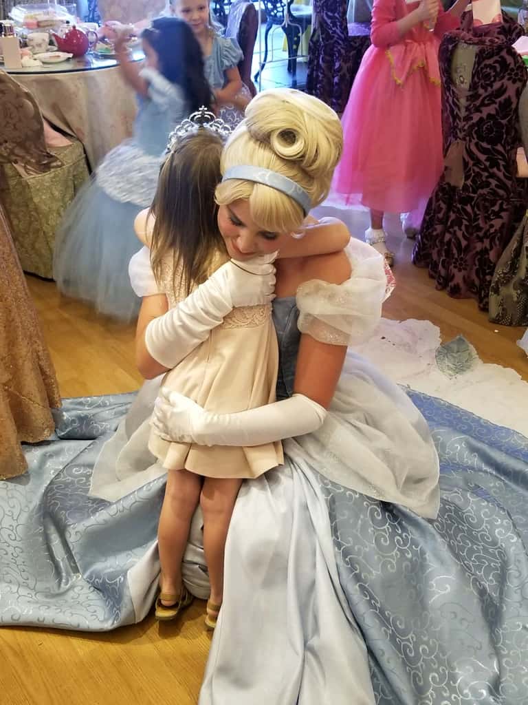 Cinderella shares a hug with a young guest at a princess party