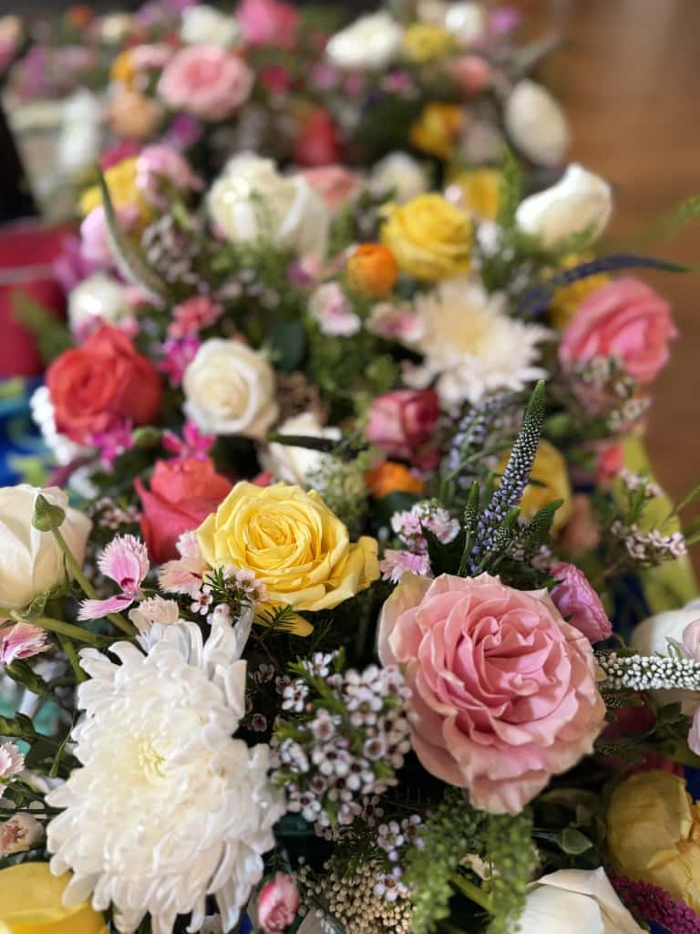 A lush close-up of a fresh-flower table runner in roses, ranunculus, and wax flower