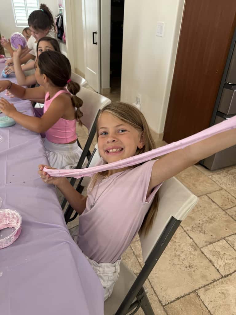 A young guest stretches freshly made slime at the craft table