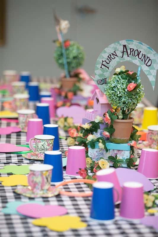 A themed table set with topiaries, patterned teacups, and hand-cut paper details