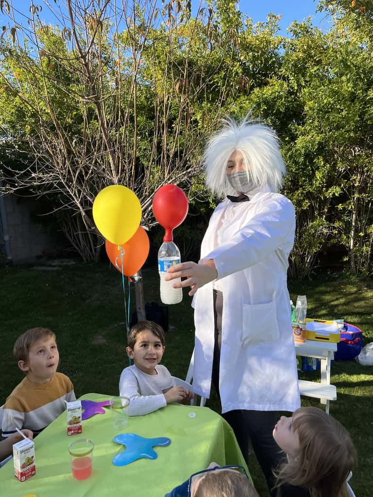 A mad-scientist performer leads a fizzing experiment for young guests at a backyard celebration
