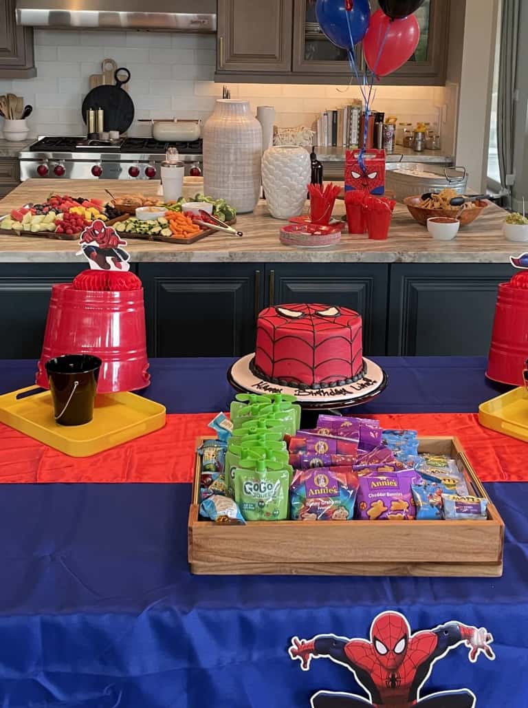 A superhero-themed spread with a custom character cake and a styled tray of packaged snacks