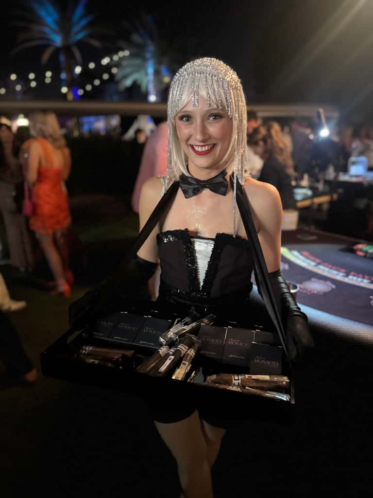 A tuxedo-styled hostess carries a tray of favors at an upscale casino-night gala