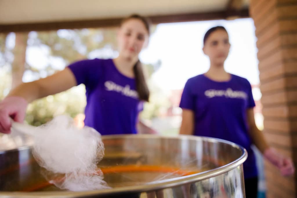 An attendant spins fresh cotton candy at a confection station