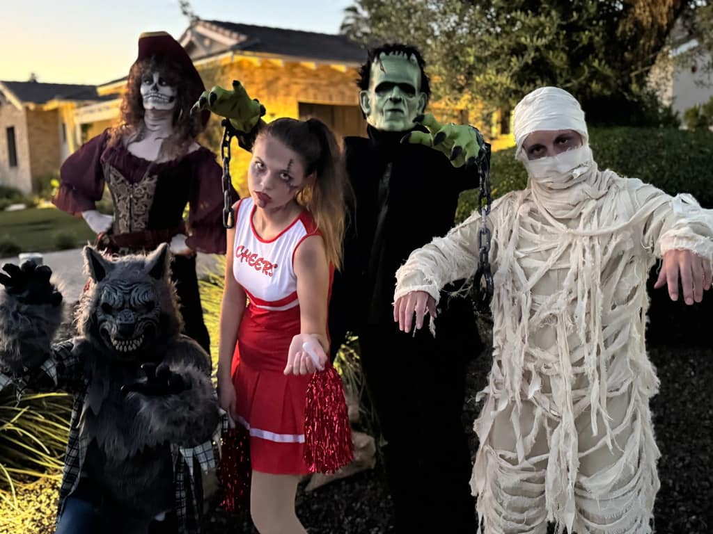 A cast of Halloween characters including Frankenstein, a mummy, a werewolf, and a cheerleader
