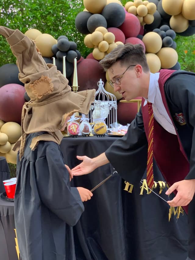 A Harry Potter character greets a child wearing a Sorting Hat at a wizarding-themed party