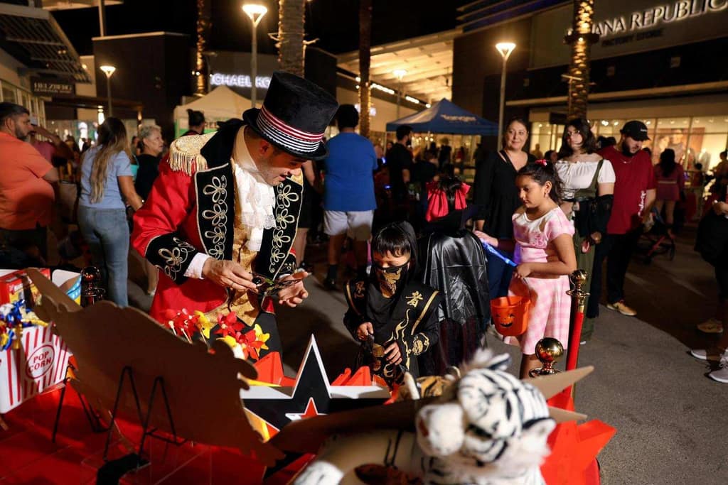A ringmaster character entertains young guests at an evening outdoor event