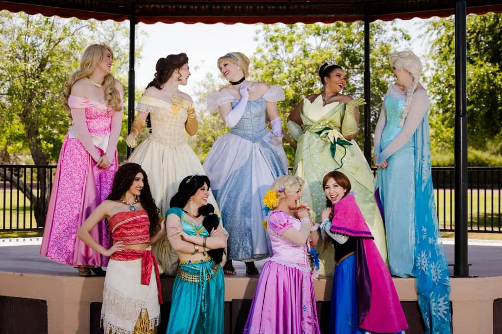 A full ensemble of princess characters posed together at an outdoor event